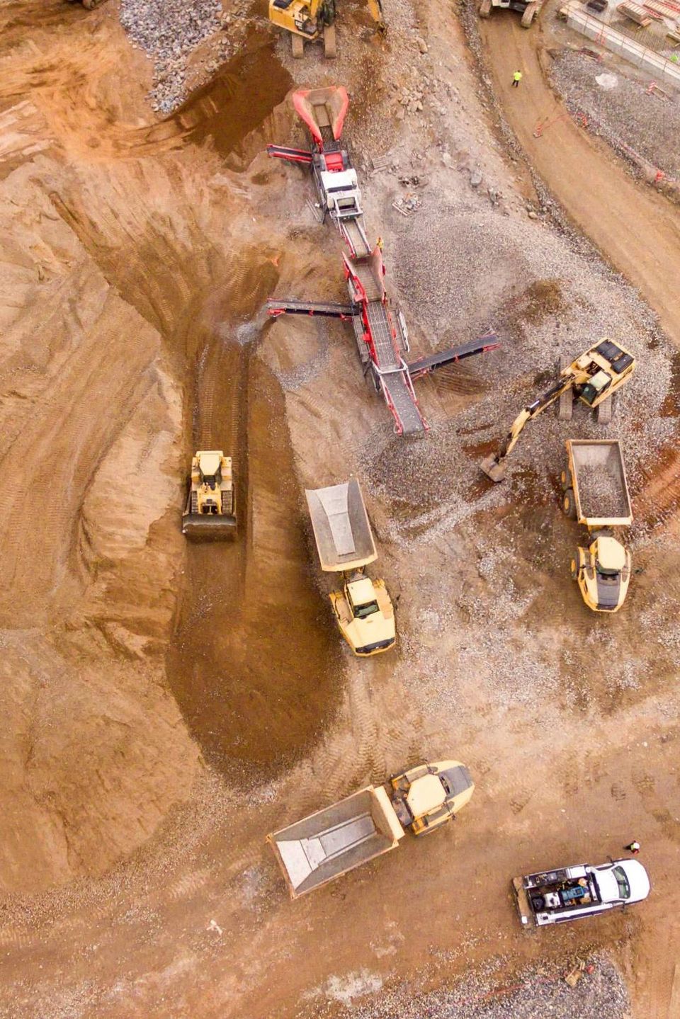 Aerial view of a construction site with excavators, dump trucks and a screening plant at work